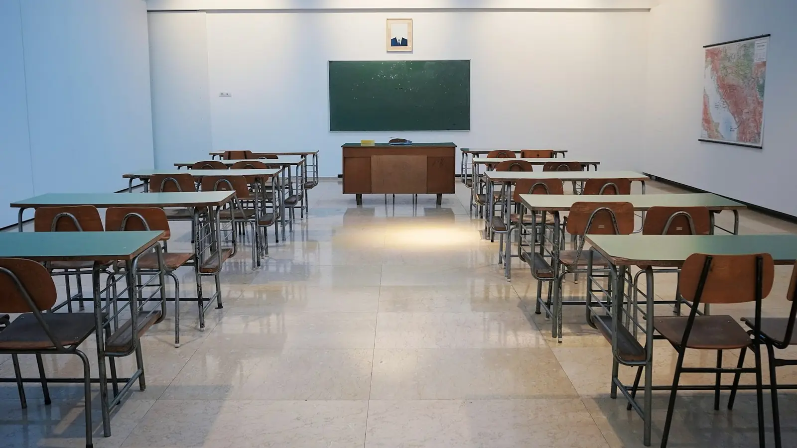 Leeg klaslokaal met rijen tafels en stoelen voor een schoolbord